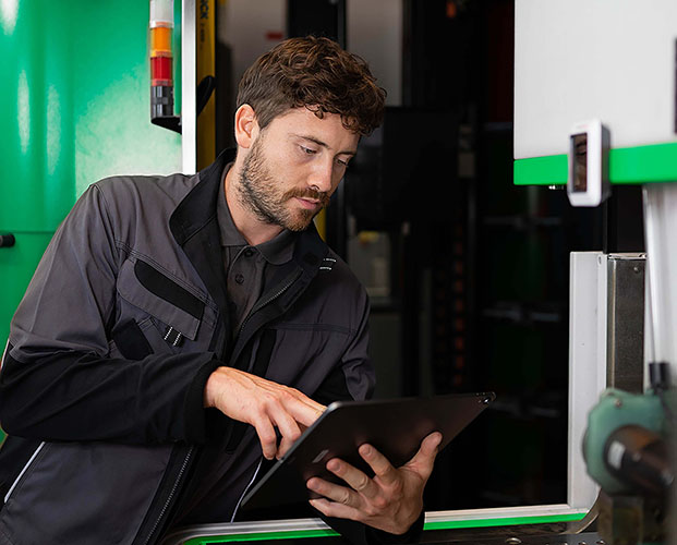 A technician uses smart service and connected worker platform on his tablet in an industrial setting.