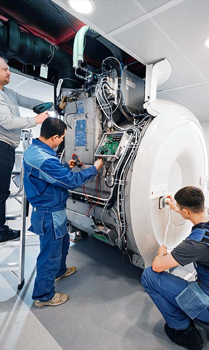 Drei Techniker reparieren einen MRI-Scanner.