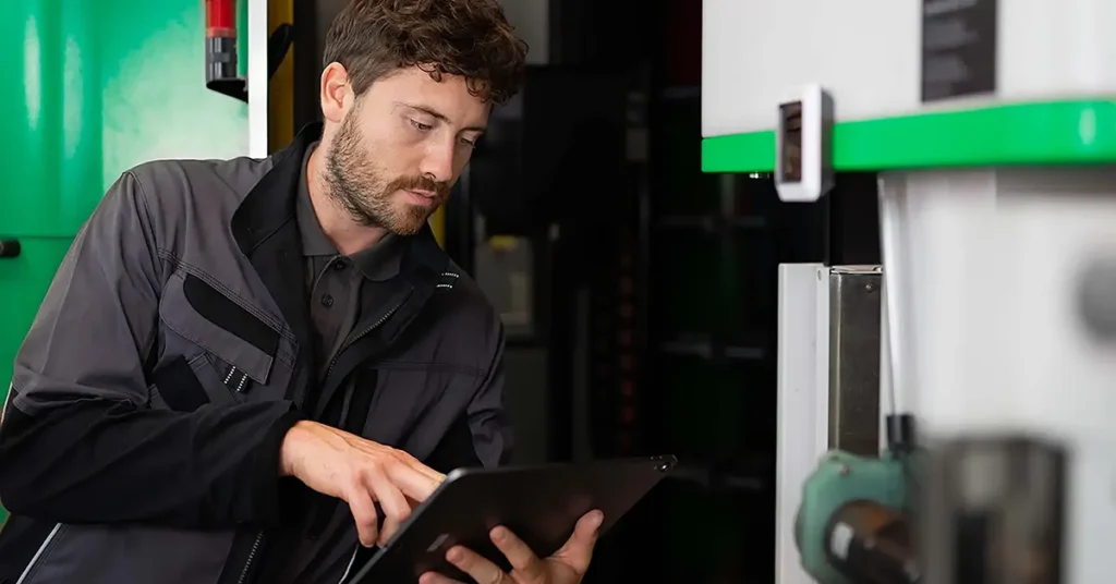 A technician uses smart service and connected worker platform on his tablet in an industrial setting.